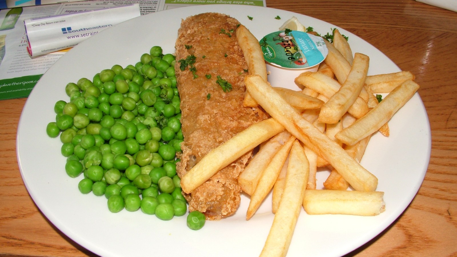 A plate of fish and chips with peas